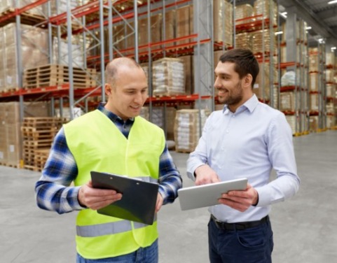 Warehouse worker in high-vis and supervisor in shirt collaborating in front of racking