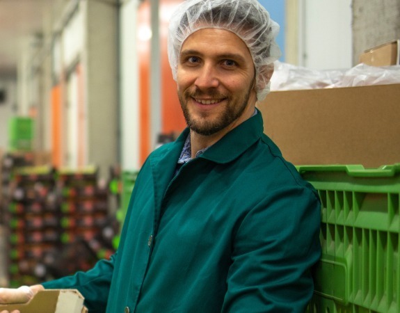 Man wearing a hairnet working in a food production facility