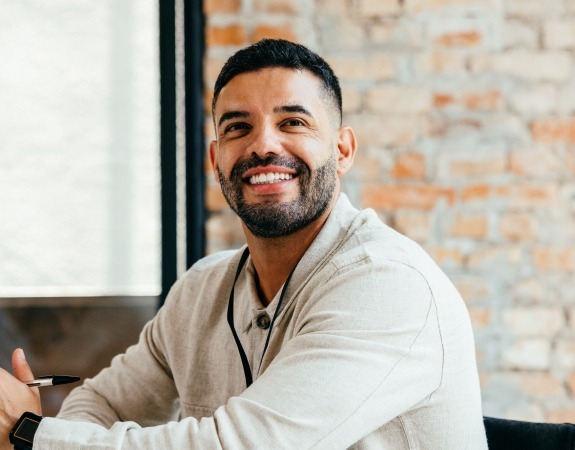Man in casual office attire smiling at his desk