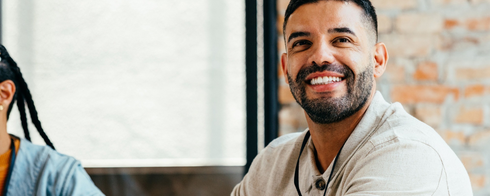Man in casual office attire smiling at his desk