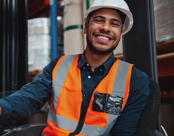 Man smiling while operating a forklift truck in a warehouse