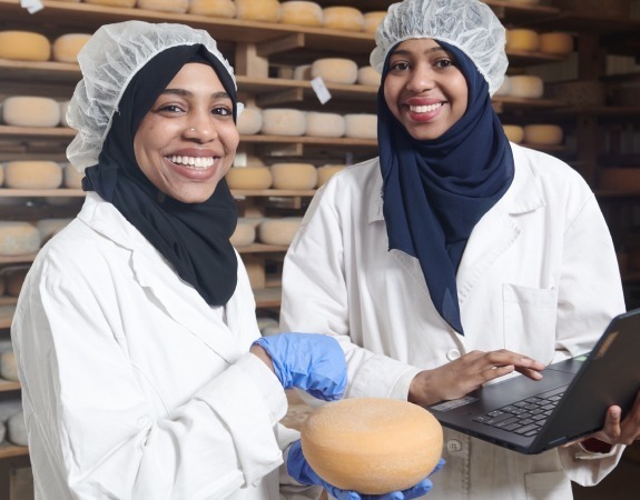 Two women in overalls working together in a bakery food production environment