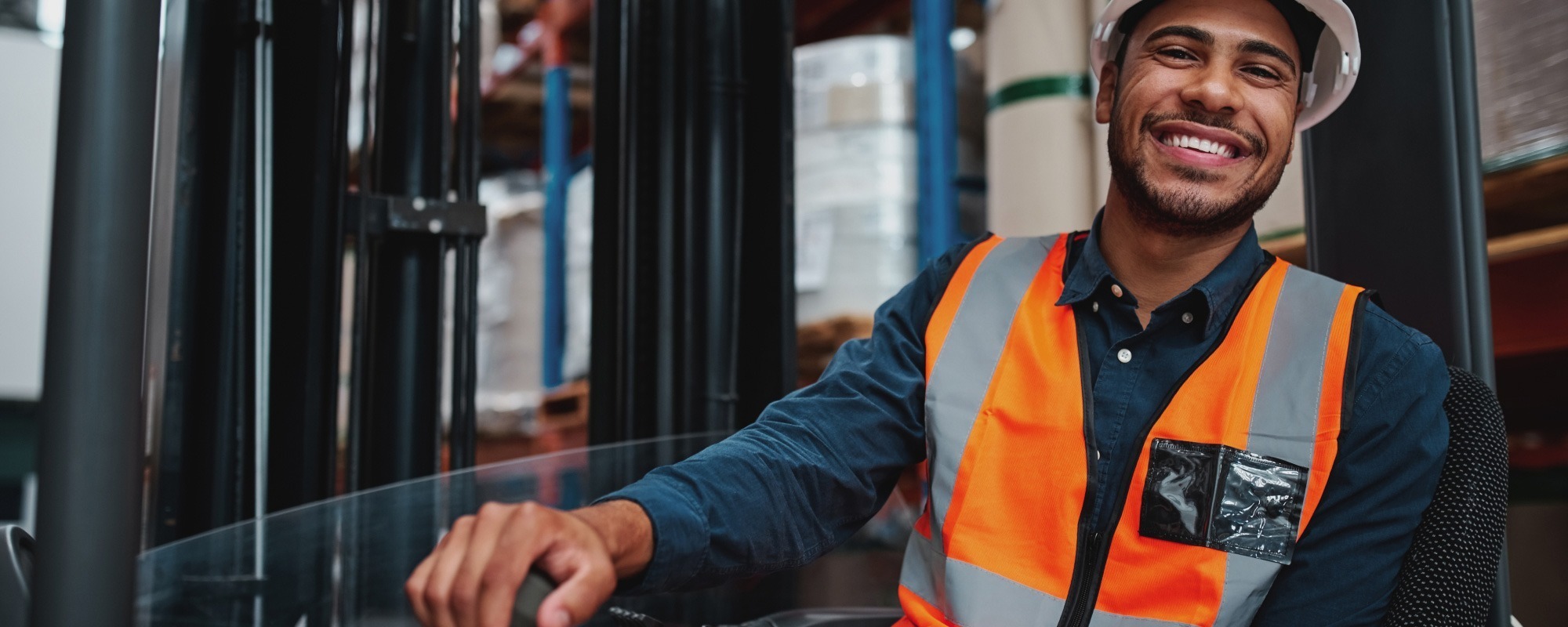 Man smiling while operating a forklift truck in a warehouse