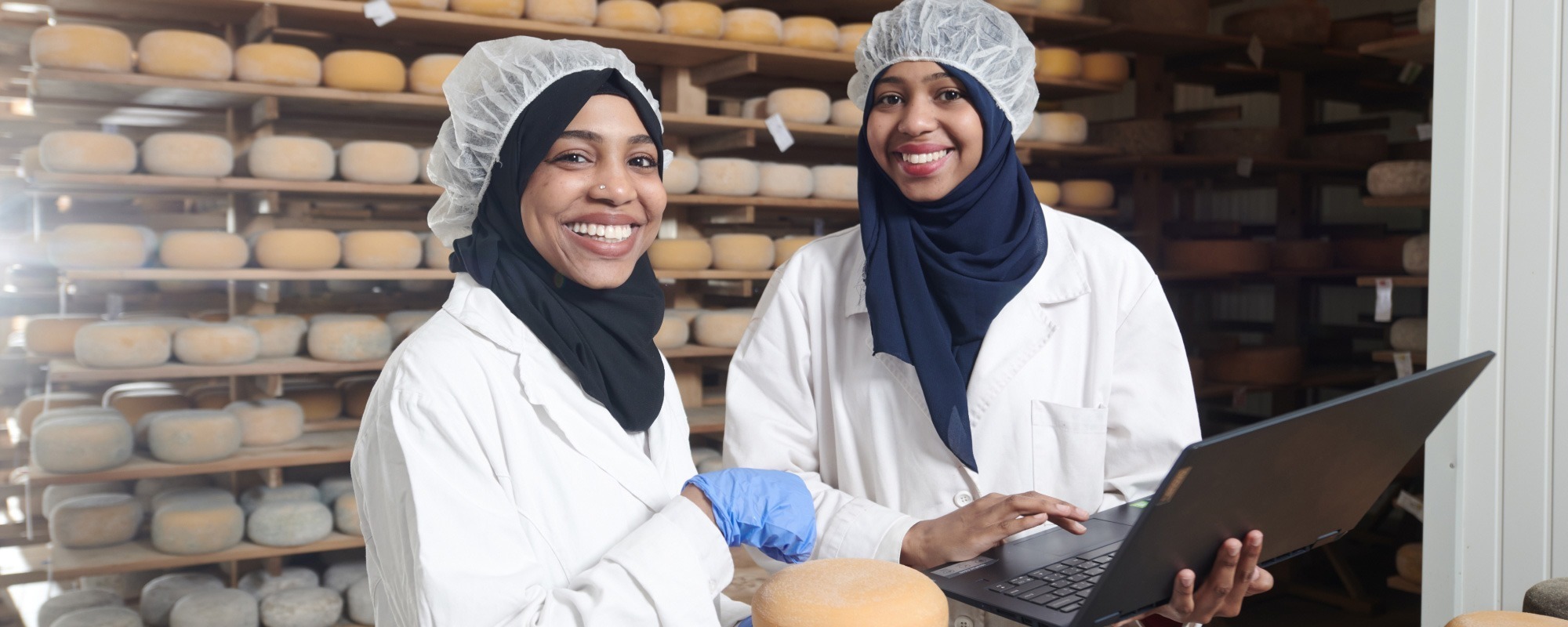 Two women in overalls working together in a bakery food production environment