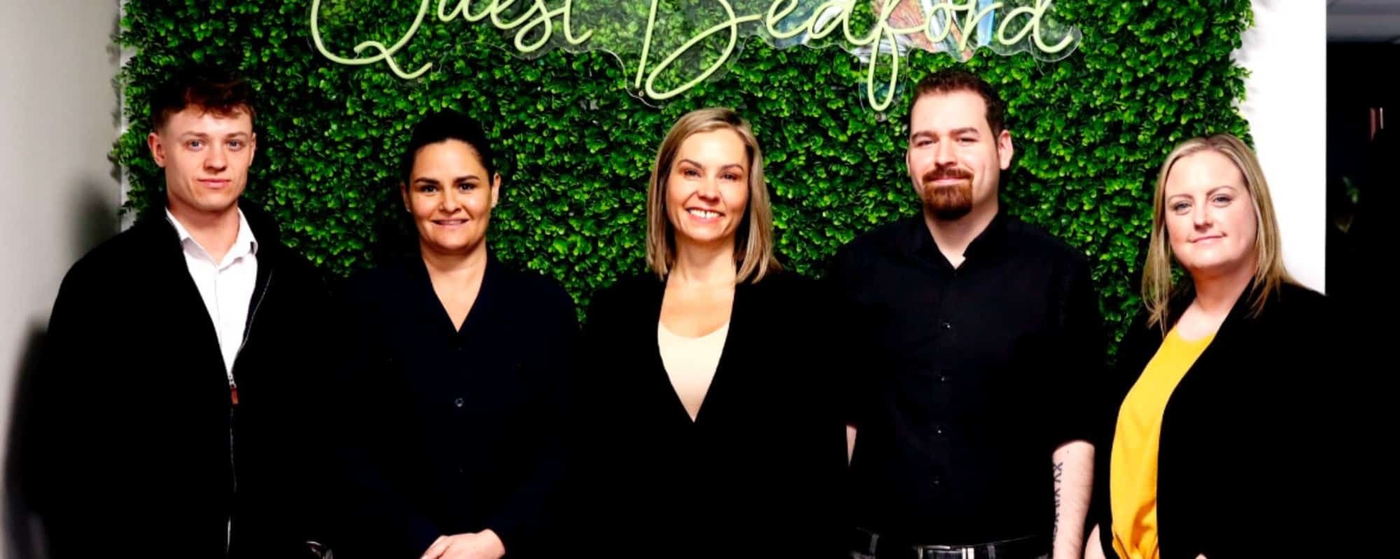 Quest Employment commercial team standing together in office for team announcement